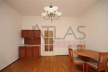 Jídelní kout s parketovou podlahou, dřevěným nábytkem a elegantním osvětlením, vhodný pro moderní bydlení v prostorném interiéru.