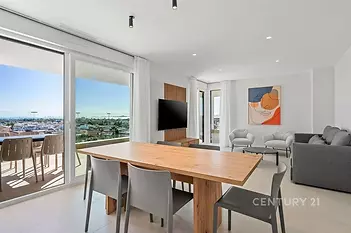 Světlý obývací pokoj s moderní dlažbou, velkými okny a vstupem na balkon, nabízí nádherný výhled na město.