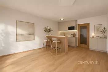 Moderní kuchyň s dřevěnou podlahou, stylovou barovou deskou a vestavěnými skříněmi, vytváří světlý a otevřený prostor.
