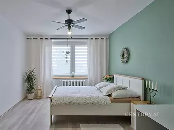 Světlá ložnice s parketovou podlahou, velkými okny.
