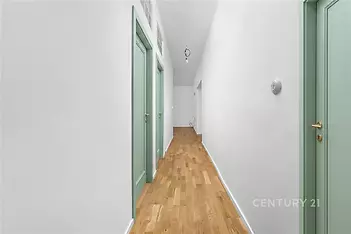 Dlouhá chodba s parketovou podlahou a světle zelenými dveřmi, bílá zeď, moderní design, světlé prostory, neutrální barevné schéma