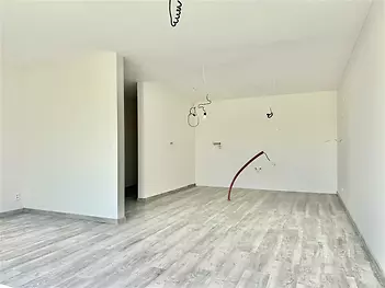 Prostorný obývací pokoj s moderní laminátovou podlahou a bílými stěnami, ideální pro vytvoření útulného rodinného prostředí.