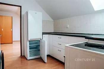 Moderní kuchyň s parketovou podlahou, vestavěné spotřebiče a světlá kachlová dlažba, podkrovní prostor s přirozeným osvětlením.