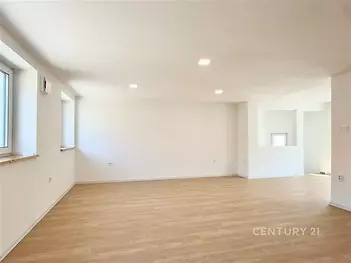 Prostorný obývací pokoj, parketová podlaha, velká okna, světlý moderní interiér.