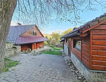 Tradiční dřevěná chalupa s pálenou střešní krytinou, kamennou dlažbou a klidným venkovním prostorem.