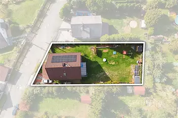 Prostorná zahrada u rodinného domu nabízí zelený trávník, vzrostlé stromy a střechu s fotovoltaickými panely; pozemek působí udržovaně