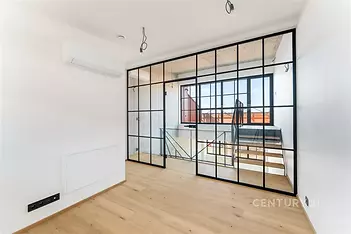 Světlý obývací pokoj s parketovou podlahou a velkými skleněnými dveřmi, moderní design a klimatizace zvýrazňují jeho stylovou úpravu.