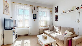 Světlý obývací pokoj s velkými okny, moderní dekorací a světlou sedačkou, parketová podlaha a bílý nábytek dodávají místnosti útulnost