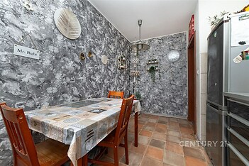 Kuchyň s originální tapetou, dlažbou a moderním vybavením. Obsahuje jídelní kout se dřevěným nábytkem a nápaditými dekoracemi.