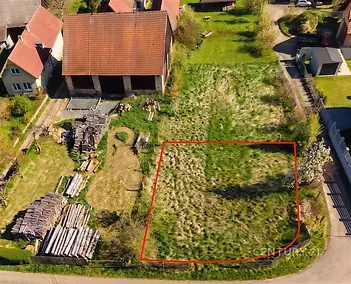 Pozemek s rovnou travnatou plochou, obklopený rodinnými domy. Vhodný pro stavbu nebo zahradu, klidná lokalita v zástavbě.