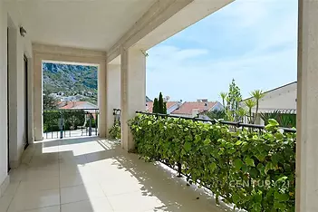 Prostorná terasa s dlažbou, výhledem na moře a okolní hory. Venkovní prostor je lemován zelení, ideální pro odpočinek a relaxaci.