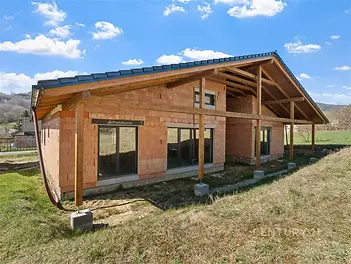 Bungalov v rekonstrukci s dřevěnou konstrukcí, velkými okny a moderním střešním designem, ideální pro milovníky přírody a klidu.