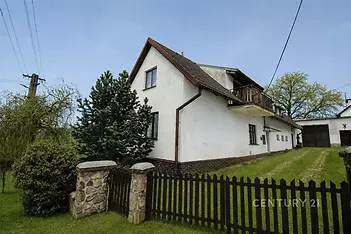 Rodinný dům s bílou fasádou a sedlovou střechou, prostorná zahrada, dřevěný plot, klidná lokalita, ideální pro rodiny