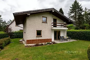 Dvoupatrový rodinný dům s terasou, obklopený udržovanou zahradou, nabízí klidné bydlení na okraji města, moderní architektura, přírodní materiály.