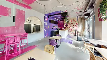 Moderní kavárna s barevným interiérem, betonová podlaha, velká okna, živé dekorace, stylové osvětlení, ideální pro kreativní podnikání.