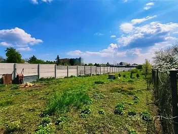 Prázdný pozemek s ohraničením, travnatý povrch, slunná lokalita v klidném prostředí, ideální pro stavbu rodinného domu nebo investiční příležitost.