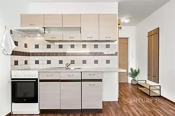 Moderní kuchyň s parketovou podlahou, světlými dřevěnými skříňkami a dlaždičkovým obkladem, světlý a účelný design