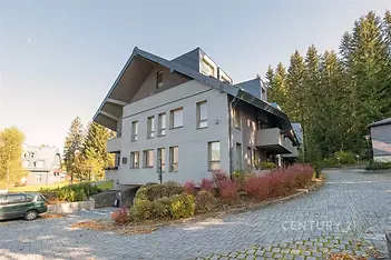 Moderní bytový dům s dřevěnou fasádou, nachází se v klidné lokalitě u lesa, disponuje velkými okny a kvalitní střešní krytinou