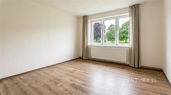 Světlá ložnice s parketovou podlahou, velká okna nabízejí pohled do zeleně, moderní zrenovovaný prostor vhodný pro klidné bydlení.
