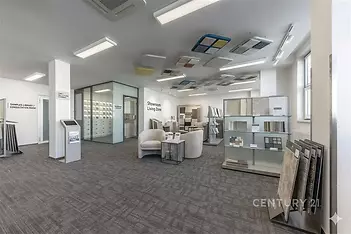 Pracovní showroom s moderním kobercem, velkým výběrem materiálů a vzorků, světlý interiér s velkými okny a skleněnými příčkami.