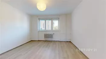 Světlý obývací pokoj s parketovou podlahou a velkými okny, moderně vymalovaný interiér s možností vlastního uspořádání nábytku.