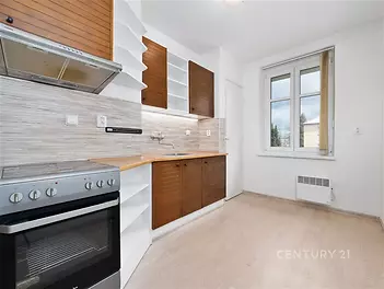 Moderní kuchyň s dřevěnou pracovní deskou, světlá parketová podlaha, vestavěné skříně, velká okna, světlý prostor, rekonstruovaný vzhled.