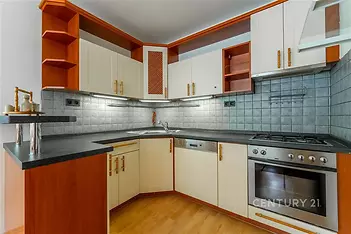 Moderní kuchyň s dřevěnými skříňkami, vestavěnou troubou a dlaždičkovým obkladem, parketová podlaha vytváří elegantní interiér.