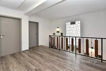 Chodba s moderním laminátovou podlahou a stylovým zábradlím, dveře v neutrálním odstínu, prostorný a světlý interiér.