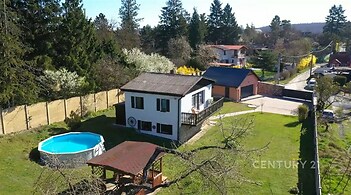 Dům na prostorném pozemku s bazénem, zahradní pergolou a garáží. Klidné prostředí obklopené zelení, ideální pro rodinné bydlení.