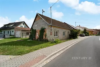 Dům na rekonstrukci s kamennou fasádou a šikmou střechou, nacházející se na klidné ulici s dlážděným chodníkem, ideální investiční příležitost.