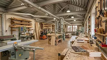 Dílna s dřevěnou parketovou podlahou, moderní vybavení, velká okna, ideální pro profesionální truhlářství nebo kutilské projekty.