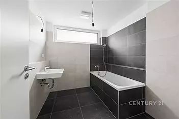 Moderní koupelna, černá a šedá dlažba, velká okna, minimalistický design, prostorný interiér, světlý prostor