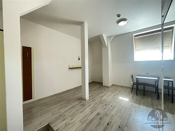 Světlá jídelna s moderní laminátovou podlahou, stůl pro dva, velké střešní okno, minimalistický design, dobré přírodní osvětlení.