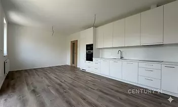 Moderní kuchyň s laminátovou podlahou, vestavěnými spotřebiči a světlými skříňkami, ideální pro otevřený koncept bydlení.