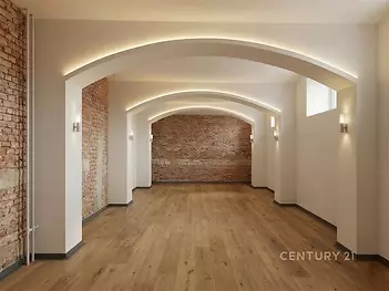 Prostorný obývací pokoj s parketovou podlahou, moderní osvětlení, cihlové zdi dodávají industriální styl, vhodný pro rekonstrukci.