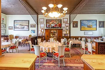 Restaurace s dřevěným stropem nabízí útulnou atmosféru, vintage dekorace a elegantní dřevěný nábytek, ideální pro příjemné stolování.
